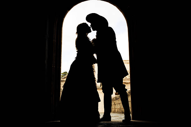 silhouette of kissing romeo and juliet silhouette of kissing romeo and juliet, creative color retouching to underline the ancient medieval time,vignetting and noise added knight person photos stock pictures, royalty-free photos & images