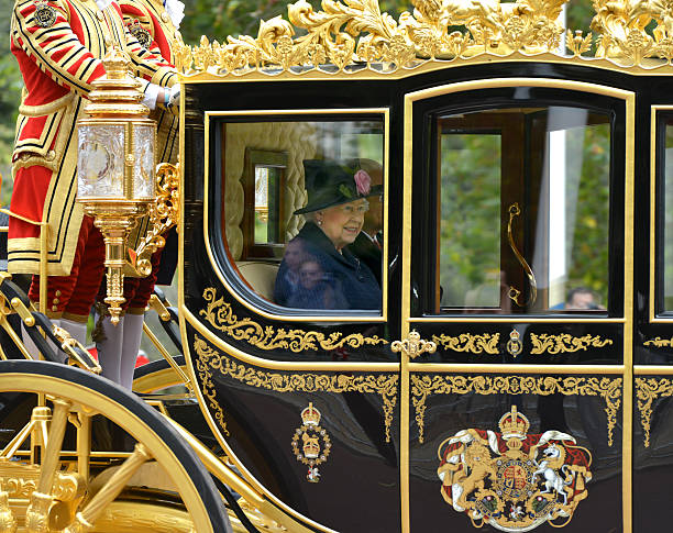 Queen passes London, UK - October 21st 2014: Queen Elizabeth II framed in the window of an ornate ceremonial coach passes along the Mall in central London during a welcome ceremony and procession for a foreign dignitary  coat of arms photos stock pictures, royalty-free photos & images