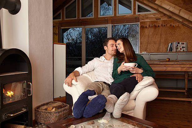 istock Couple sitting by fireplace and drinking tae 467131474