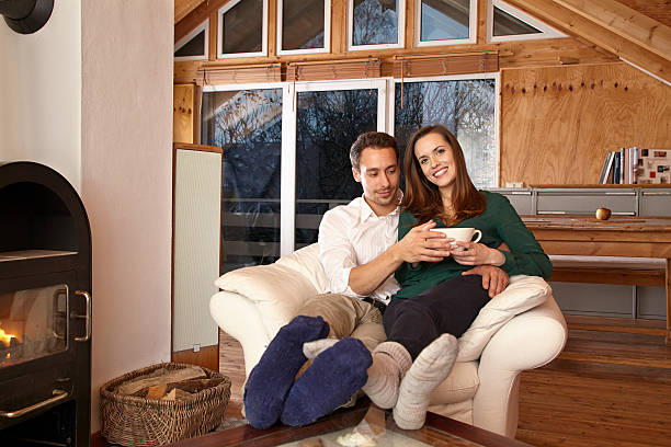 istock Couple sitting by fireplace and drinking tae 467131478