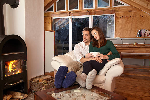 istock Couple sitting by fireplace and drinking tae 467131488