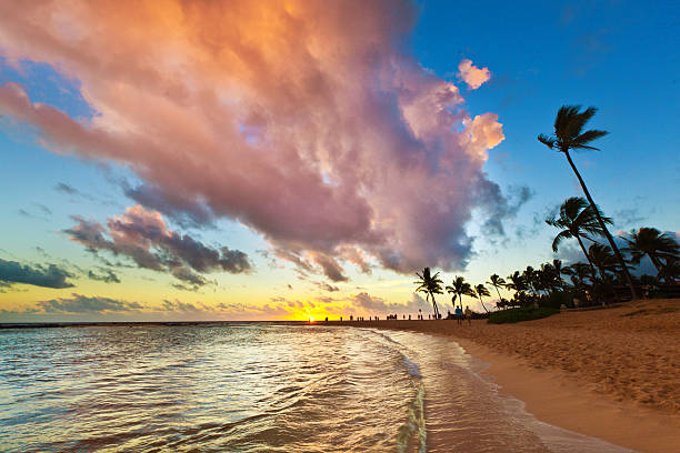 Tourists and visitors gather to watch the sunset at Poipu Beach of Kauai, Hawaii.