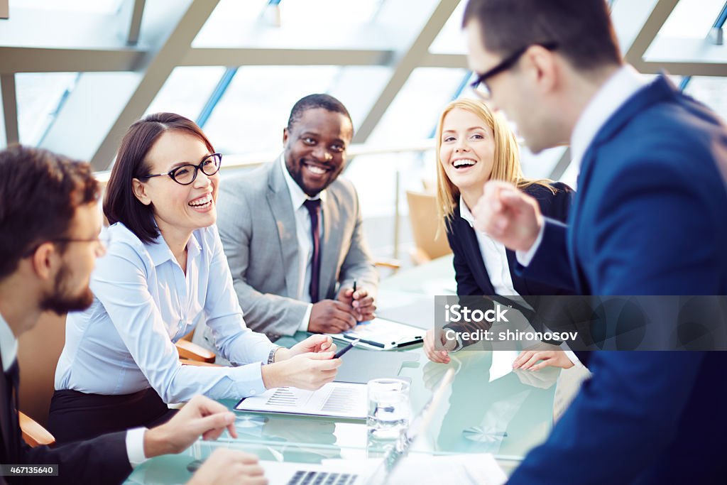 A cheerful discussion between businesspeople Business people laughing together at meeting 2015 Stock Photo