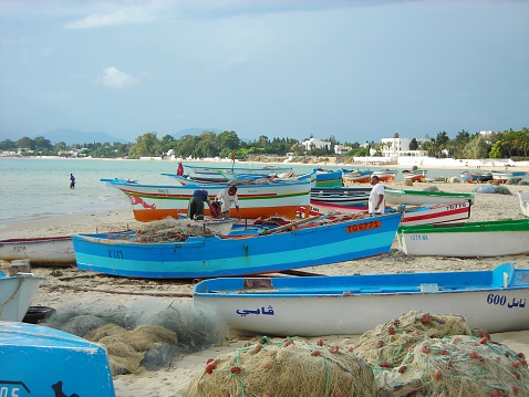 Hammamet, Tunisia - September 25, 2008: Fishermen rearrange their fishing boats and nets on the beach, just before the storm, in the Tunisian seaside resort of Hammamet.
