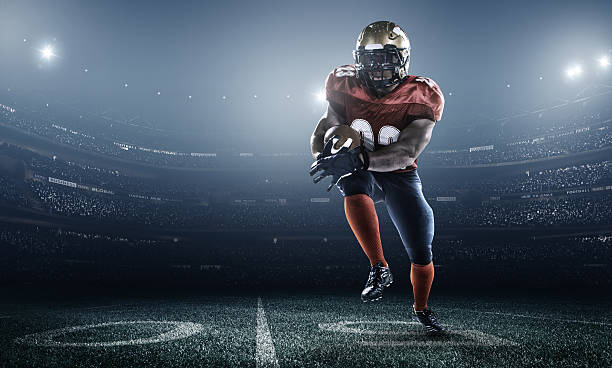 American football in action American football player with a red uniform, in dark stadium with full of spectators under night sky Touchdown stock pictures, royalty-free photos & images