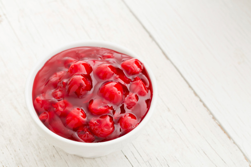 An overhead close up shot of a bowl full of cherry pie filling.