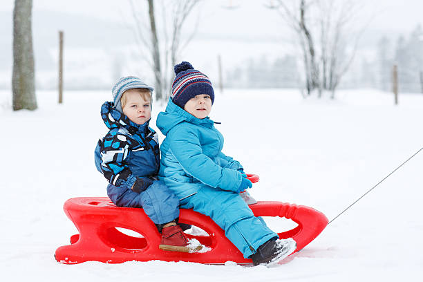 istock Two little siblings having fun on sledge in winter 467151929