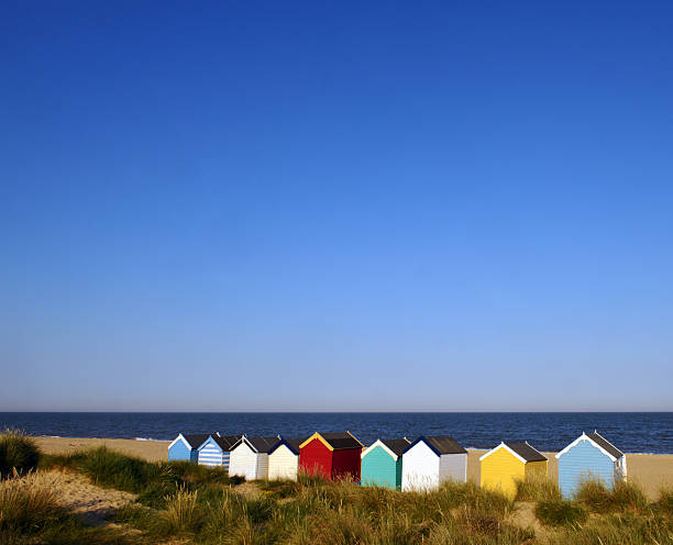 Beach Huts Colourful vacation beach huts beside the ocean with clear blue sunny summers day  southwold stock pictures, royalty-free photos & images