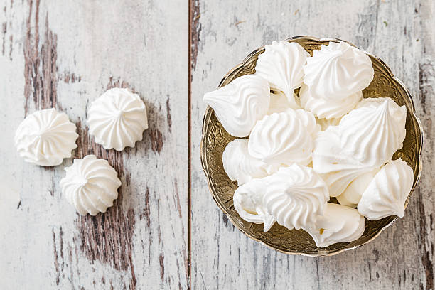 Bowl filled with vanilla meringue cookies Delicious and plain white vanilla meringue cookies in silver traditional  bowl meringue stock pictures, royalty-free photos & images