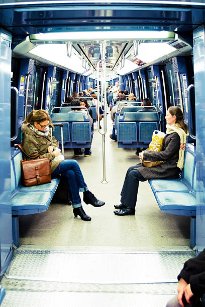 Paris, France - November 13, 2013: Passengers inside metro train in Paris. Two woman on foreground, numerous people on background.