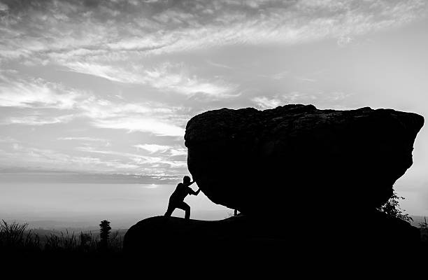 Hard work.The person rolls the rock on mountain