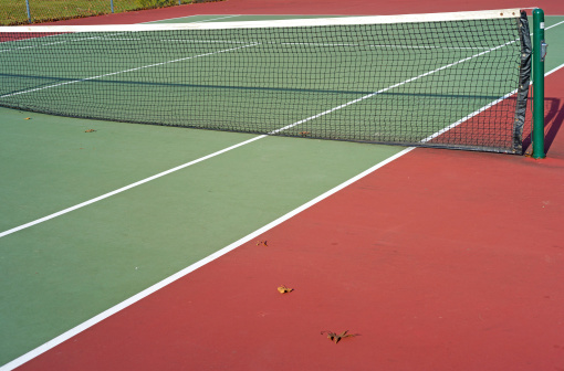A deserted tennis court with net divider.
