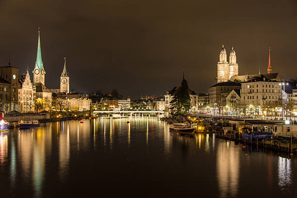 zurigo sulle rive del fiume limmat alla sera d'inverno - grossmunster cathedral foto e immagini stock