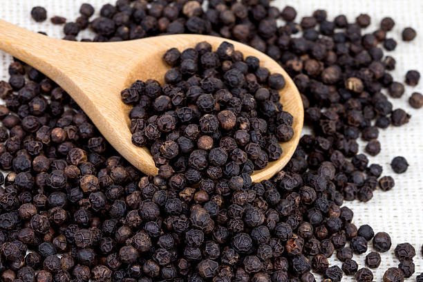 istock closeup black pepper in wooden spoon on fabric 467196416