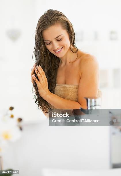 Happy Young Woman Applying Hair Mask In Bathroom Stock Photo - Download Image Now - Applying, Domestic Bathroom, Human Hair