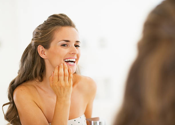 istock Happy young woman checking teeth in mirror 467198431