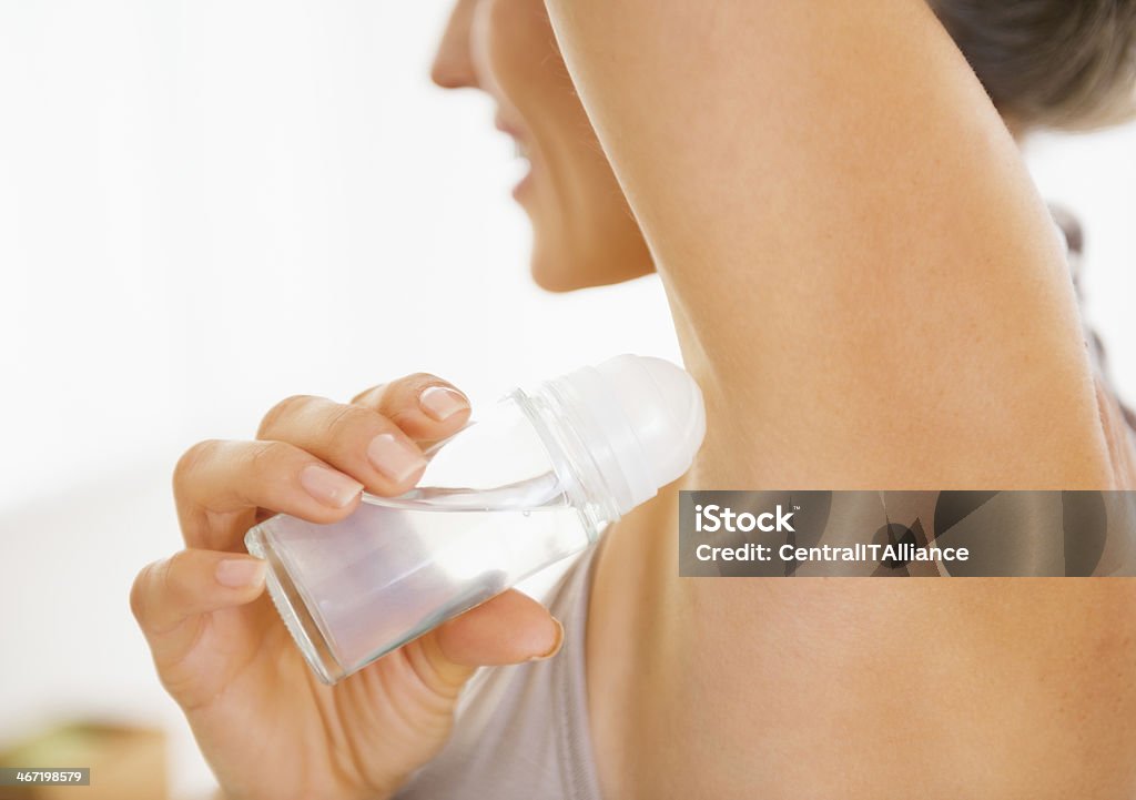 Young woman applying deodorant on underarm. Closeup Closeup on young woman applying deodorant on underarm Adult Stock Photo