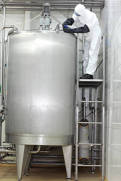 Technician closing large industrial process tank in factory Technician in protective overall closing large industrial process tank in factory mixing vat stock pictures, royalty-free photos & images