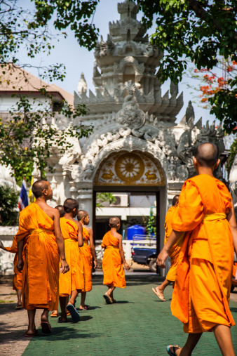 Chiang Rai, Thailand - May 2, 2013: Young buddhist monks walking in the grounds of the temple named Wat Klang Wiang in Chiang Rai, Thailand.