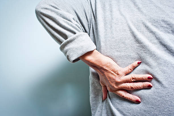 Woman with a lower back ache bent over in pain stock photo