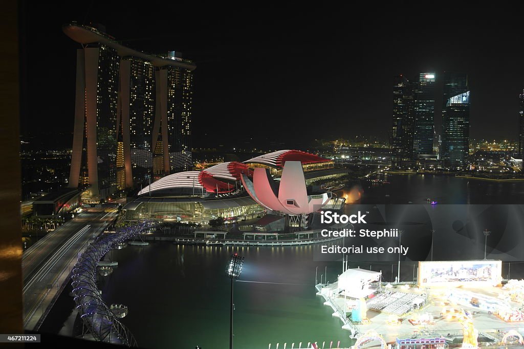 Helix Bridge to the Marina Bay Sands Hotel Singapore, Singapore - February 16, 2015: Night view of the pedestrian Helix Bridge, a structure of glass and stainless steel leading to the famous Marina Bay Sands Hotel. In the foreground are preperations for the Chines New Year. 2015 Stock Photo