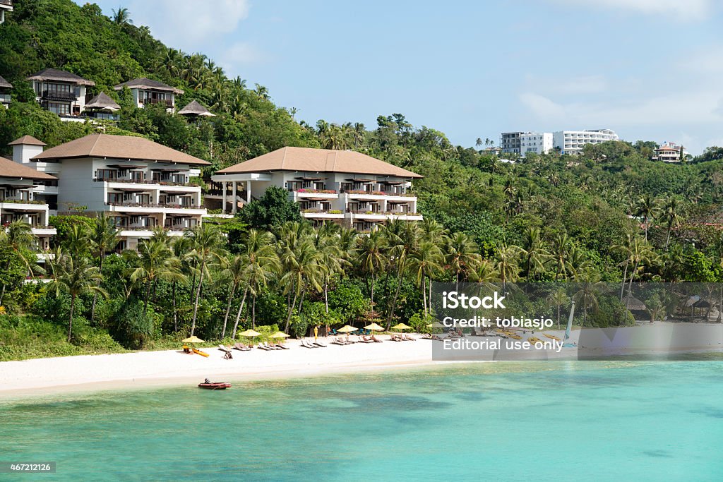 Paradise Island of Boracay Boracay, Philippines - February 28, 2015: Beach view at the paradise island of Boracay during a hot summer day. People resting on their sun beds under the parasols. Luxury villas seen behind the beach and the crystal clear ocean. 2015 Stock Photo