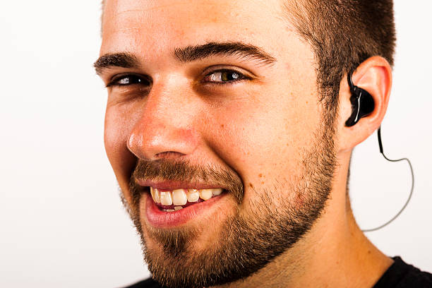 Portrait of a beautiful friendly young man Portrait of a beautiful friendly young man, listening to music, with in ear headphones lacher stock pictures, royalty-free photos & images