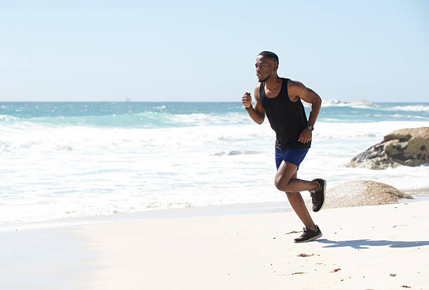 istock Active african american man running by water on the beach 467216580
