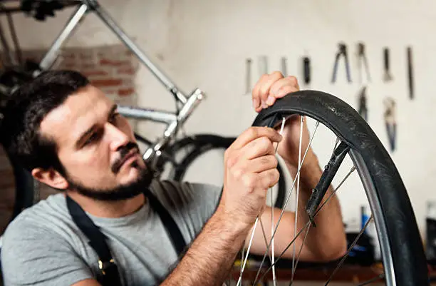 Bike mechanic using a pair of tire levers to remove the tire from the wheel.