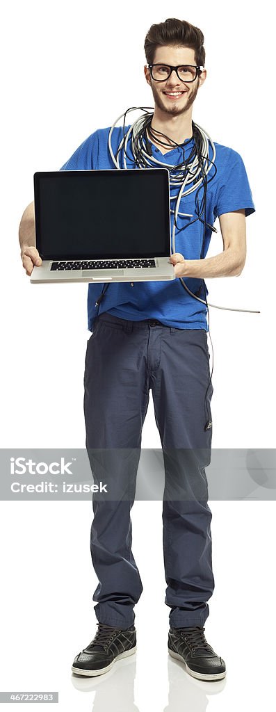 Geek Portrait of  young man with computer cables on his neck holding laptop and smiling at the camera. Studio shot, white background. Cut Out Stock Photo