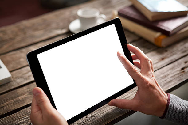 istock Man's hands holding a tablet with blank screen on wood table 467228484