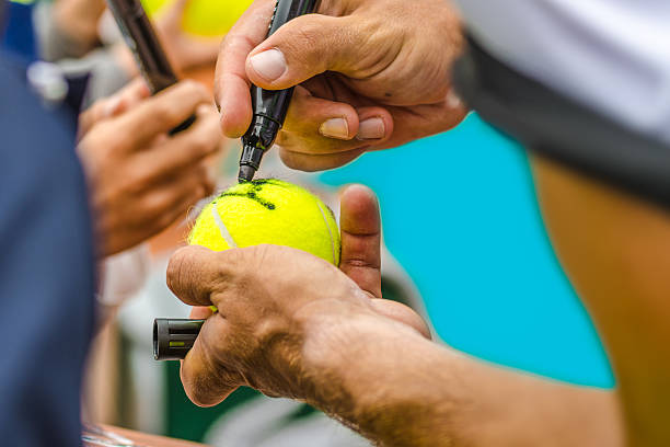 Tennis player signing autograph on a ball stock photo