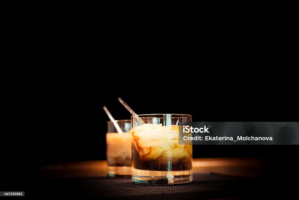 White russian cocktail Two white russian cocktails on the bar stand on rubber mat. Shallow DOF and marsala tonned White Russian Stock Photo