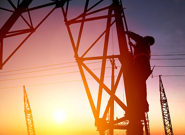 Worker at an electric substation with sunset background Worker at an electric substation with sunset background electricity substation photos stock pictures, royalty-free photos & images