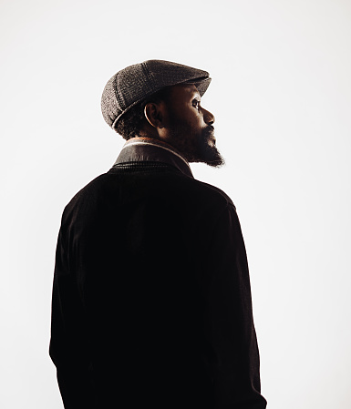 Portrait of a bearded elegant afro american man wearing a scarf and a cap. Sharp focus on eyes. Studio shot and white background. Sharp focus on eyes.