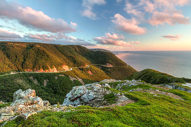 Green Cliffs Overlooking Cabot Trail The winding Cabot Trail road seen from high above on the Skyline Trail at sunset in Cape Breton Highlands National Park, Nova Scotia gulf of st lawrence photos stock pictures, royalty-free photos & images