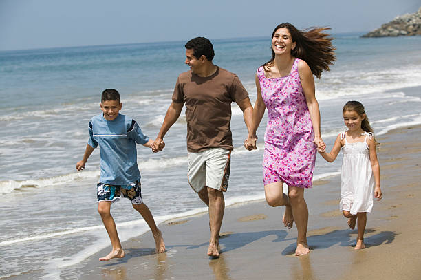 istock Family Holding Hands While Running On Beach 467244353