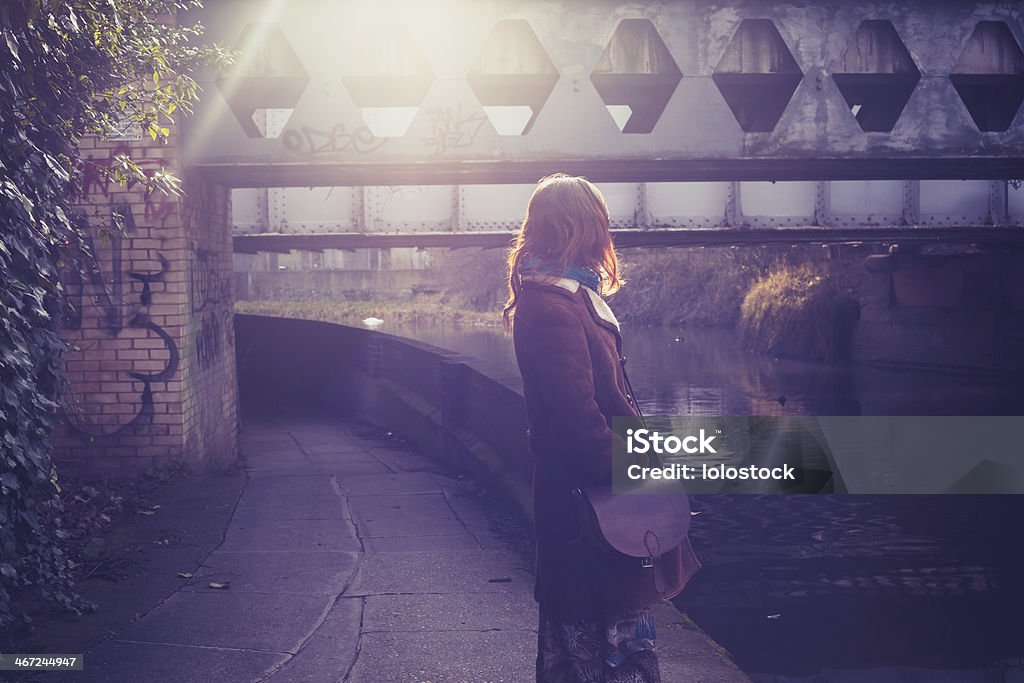 Young woman by canal at sunset Young woman is standing by canal at sunset Loneliness Stock Photo