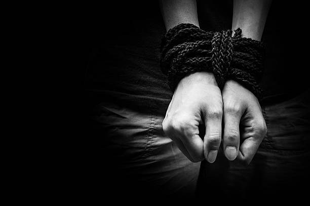 Hands of a missing kidnapped, abused, hostage, victim woman tied Hands of a missing kidnapped, abused, hostage, victim woman tied up with rope in emotional stress and pain, afraid, restricted, trapped, call for help, struggle, terrified, locked in a cage cell. people trafficking stock pictures, royalty-free photos & images