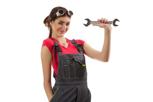 The girl stands with a wrench in her hand