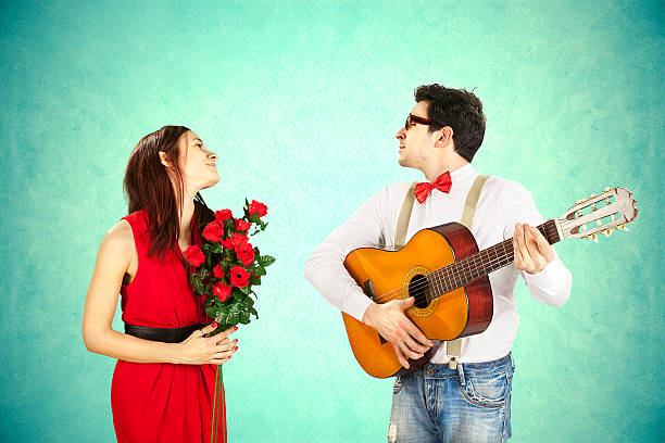 Man approaching woman playing a love song, serenade stock photo