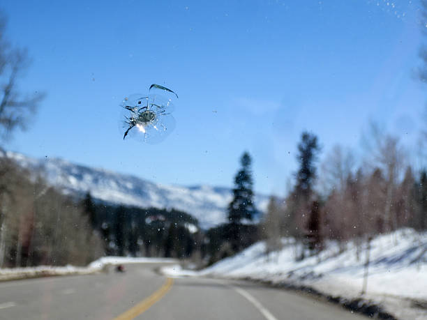 Chipped windshield with road and snow covered mountains Road, mountain and snow windshield stock pictures, royalty-free photos & images
