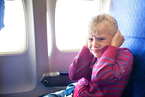 girl closing ears in the airplane stock photo