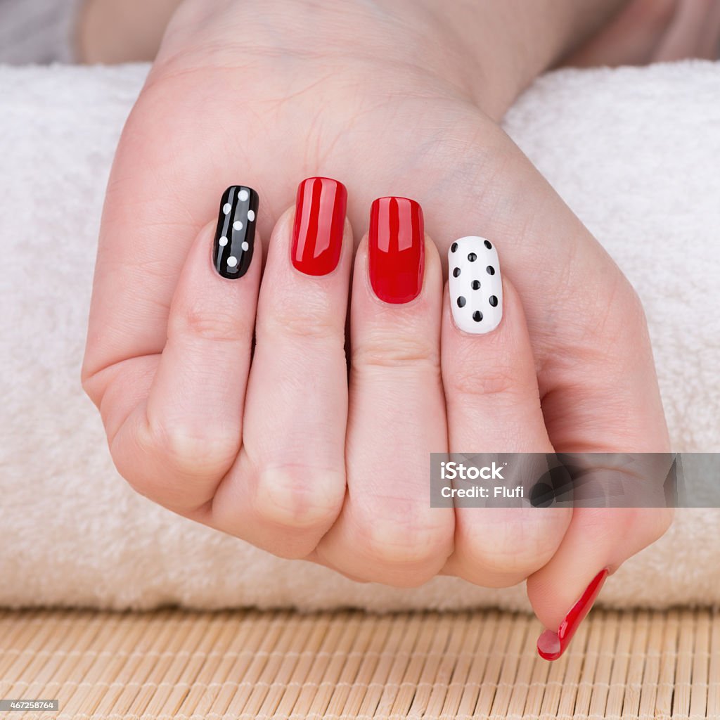 Manicure Beauty treatment photo of nice manicured woman fingernails. Very nice feminine nail art with nice red, white and black nail polish. 2015 Stock Photo