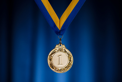 Gold medal in the foreground on yellow blue ribbon