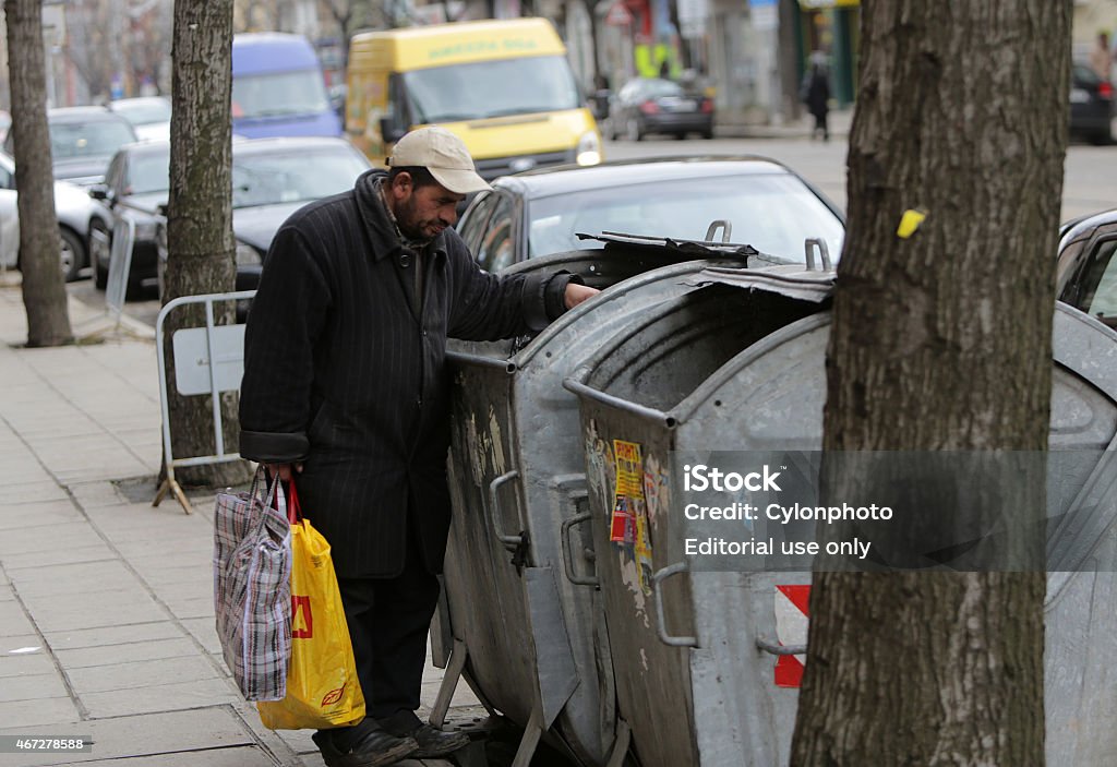 Homeless trash can Sofia, Bulgaria - March 16, 2015: A homeless man is searching the trash in a trash cans on a busy street in the center of Sofia. 2015 Stock Photo