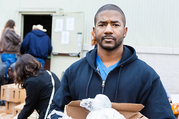 homem segurando uma caixa de doação comestíveis ao ar livre no banco alimentar - homelessness food in a row people - fotografias e filmes do acervo