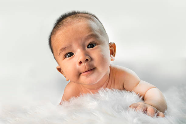 istock Peaceful newborn baby lying on a bed smiling on white 467287038
