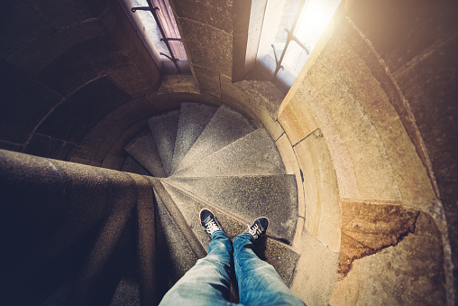 Personal perspective: young man in casual clothes looking down on spiral staircase inside of St Vitus bell tower in Prague (Czech Republic).