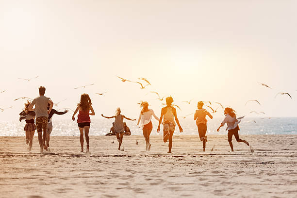 groupe d'amis courir sur la plage - shorts rear view summer beach photos et images de collection